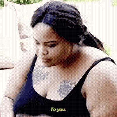 Woman With Chest Tattoo Talking On Couch GIF