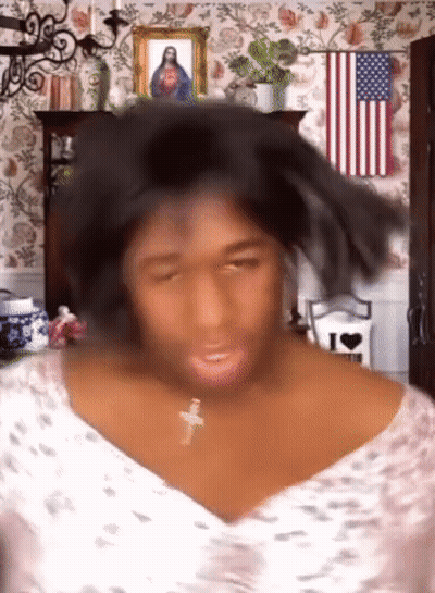 Woman With Cross Necklace In Front Of American Flag And Jesus Picture GIF