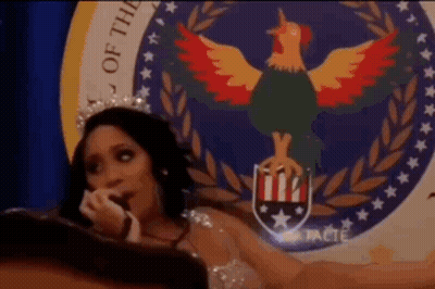 Woman With Crown Sitting In Front Of Seal With Rooster GIF