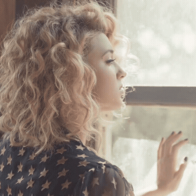Woman With Curly Blonde Hair Looking Out Window GIF