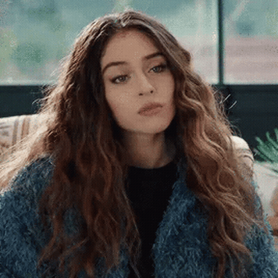 Woman With Curly Hair And Blue Fur Coat On Couch GIF