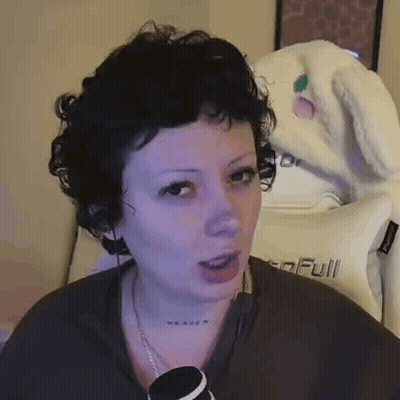 Woman With Curly Hair And Neck Tattoo Sitting In Front Of Heaven Pillow GIF
