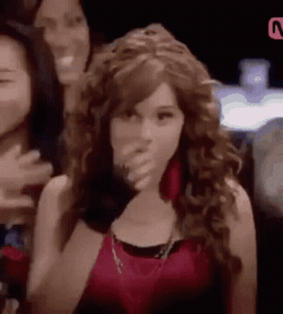Woman With Curly Hair Covering Mouth In Front Of Group GIF
