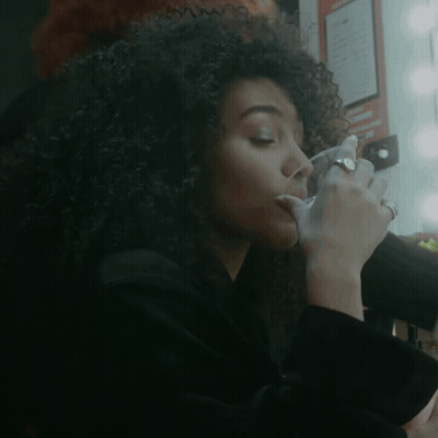 Woman With Curly Hair Drinking From Glass GIF