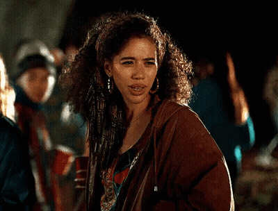 Woman With Curly Hair In Brown Jacket And Earrings In Crowd GIF