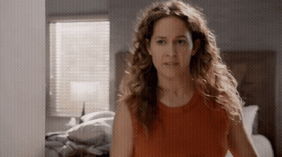 Woman With Curly Hair in Front of Bed