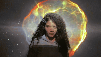 Woman With Curly Hair In Front Of Glowing Object GIF