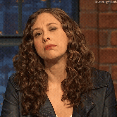 Woman With Curly Hair In Leather Jacket Making Face GIF