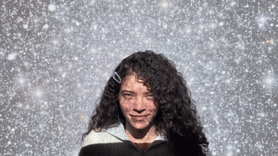 Woman With Curly Hair In Snowy Sky GIF