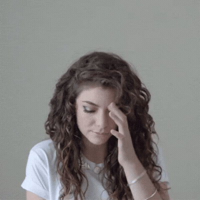 Woman With Curly Hair In White Shirt And Necklace GIF