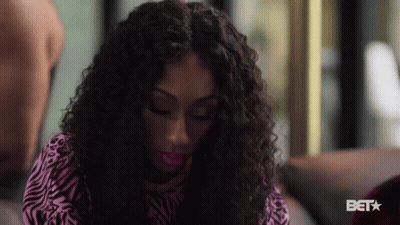 Woman With Curly Hair In Zebra Print Shirt On Couch GIF
