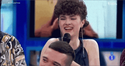 Woman With Curly Hair Laughing At Microphone On TV Show GIF