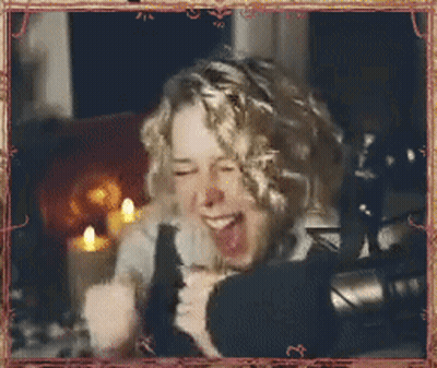 Woman With Curly Hair Laughing Into Microphone GIF