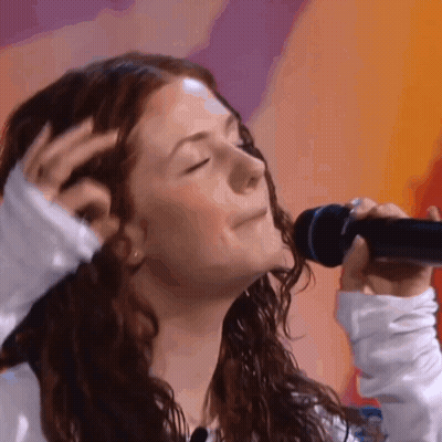Woman With Curly Hair Singing Into Microphone GIF