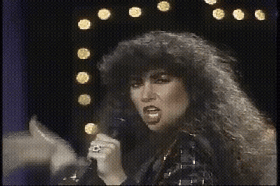 Woman With Curly Hair Singing Into Microphone GIF