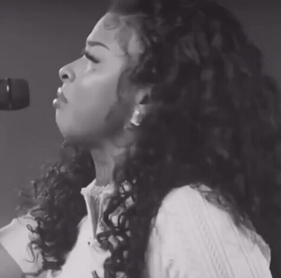 Woman With Curly Hair Singing Into Microphone