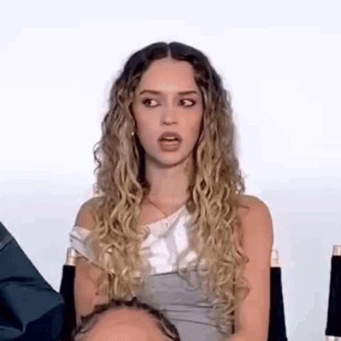 Woman With Curly Hair Sitting In Chair Making Funny Face GIF