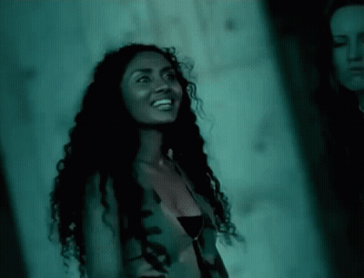 Woman With Curly Hair Smiling Next To Another Woman GIF