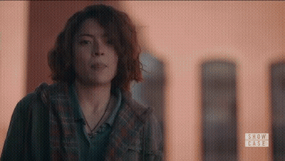 Woman With Curly Hair Standing In Front Of Building GIF