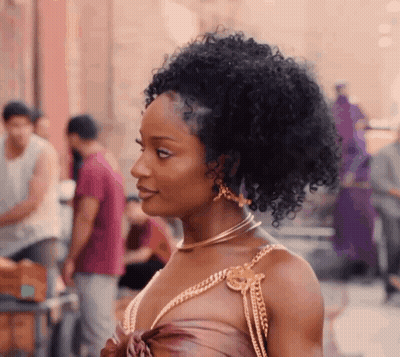 Woman With Curly Hair Wearing Necklace And Earrings On Street GIF