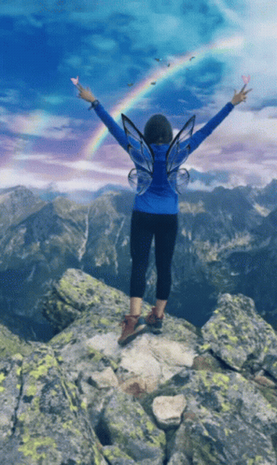Woman With Fairy Wings Arms Outstretched On Mountain GIF