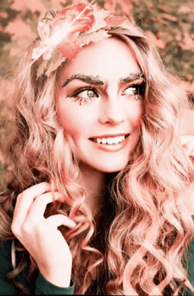 Woman With Flower In Hair And Leaves On Eyebrows GIF