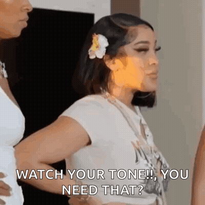 Woman With Flower In Hair Standing Next To Another Woman GIF