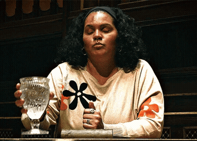 Woman With Flower On Sweater Holding Glass GIF