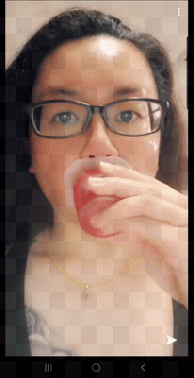 Woman With Glasses And Cross Necklace Holding Red Cup In Mouth GIF