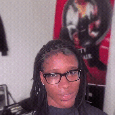 Woman With Glasses And Dreadlocks In Front Of T.I. Air Poster GIF