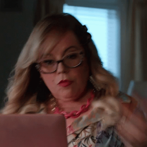 Woman With Glasses And Pink Necklace Looking At Pink Laptop GIF