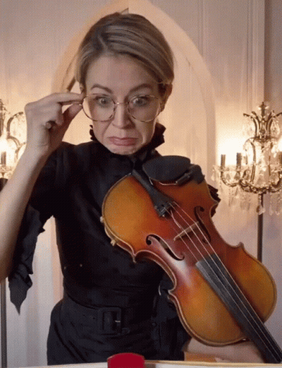 Woman With Glasses Holding Violin Making Face GIF