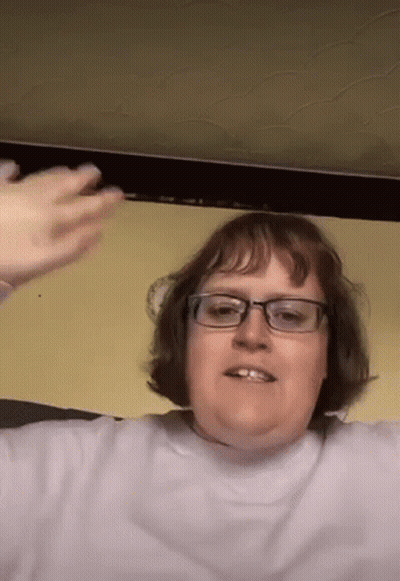 Woman With Glasses In Purple Shirt Sitting In Front Of Yellow Wall GIF