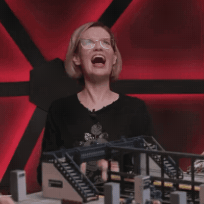 Woman With Glasses Laughing In Front Of Model Bridge GIF