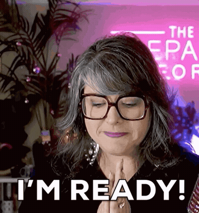 Woman With Glasses Says I'm Ready In Front Of Pink Sign GIF