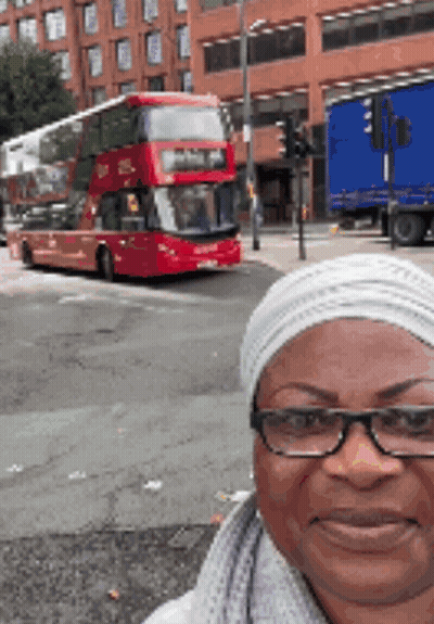 Woman With Glasses Taking Selfie In Front Of Double Decker Bus GIF