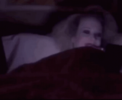 Woman With Glowing Eyes Smiling In Bed GIF