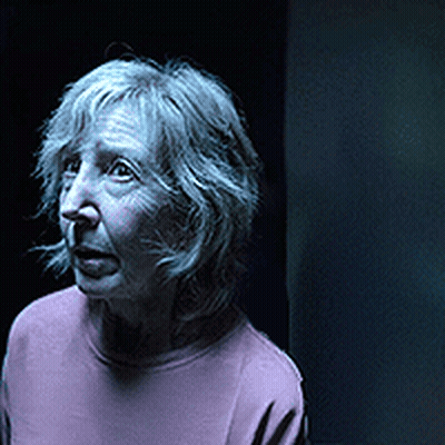 Woman With Gray Hair And Pink Shirt Looking At Camera GIF