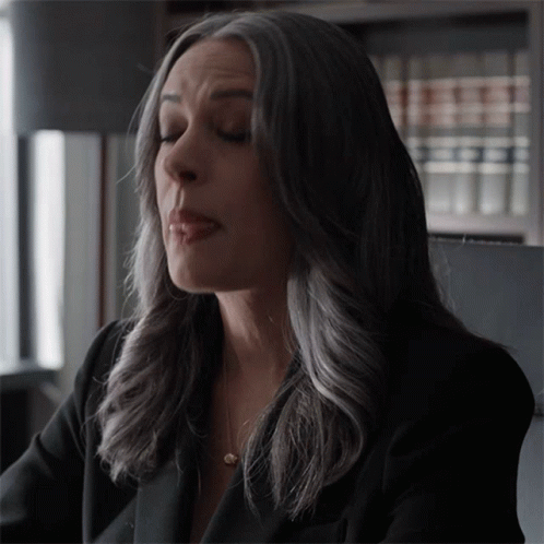 Woman With Gray Hair Sitting In Front Of Bookcase GIF