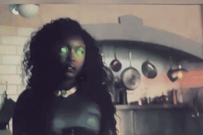 Woman With Green Eyes In Kitchen With Hanging Pots And Pans GIF