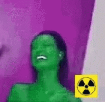 Woman With Green Hair Laughing in Front of Purple Wall With Yellow Nuclear Symbol