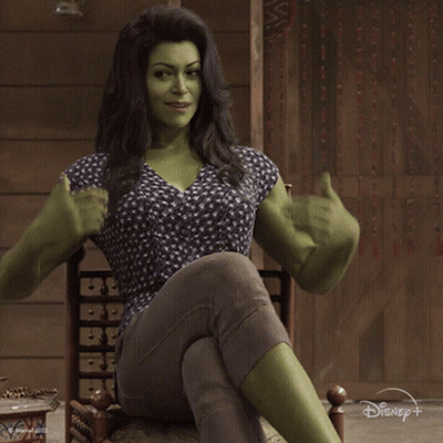 Woman With Green Muscles Sitting In Chair Saying Hello GIF