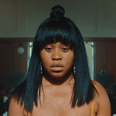 Woman With Hair Bun Looking At Camera GIF