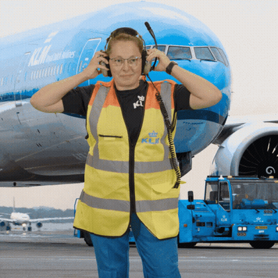 Woman With Headphones In Front Of Blue KLM Airplane GIF