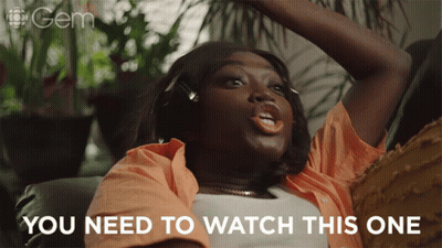 Woman With Headphones Sitting On Couch Saying You Need To Watch This One GIF