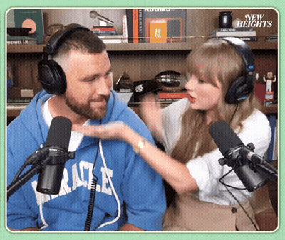 Woman With Headphones Talking To Man In Blue Miracle Sweatshirt GIF