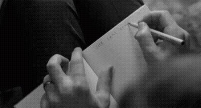 Woman With Headphones Writing At Desk GIF