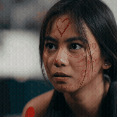 Woman With Heart Drawn On Face Looks At Camera GIF