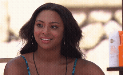 Woman With Hoop Earrings Smiling Next To Sunscreen Bottles GIF