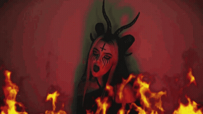 Woman With Horns And Cross Face In Front Of Fire GIF